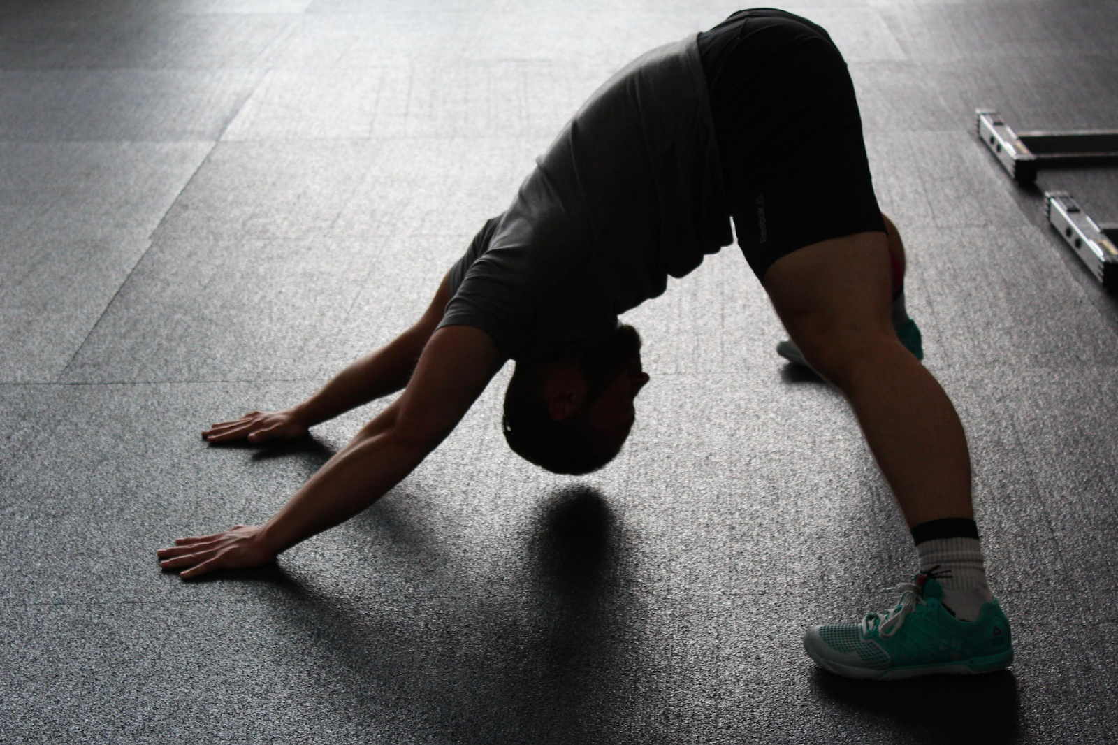 A man performs a stretch with arms and legs spread apart.