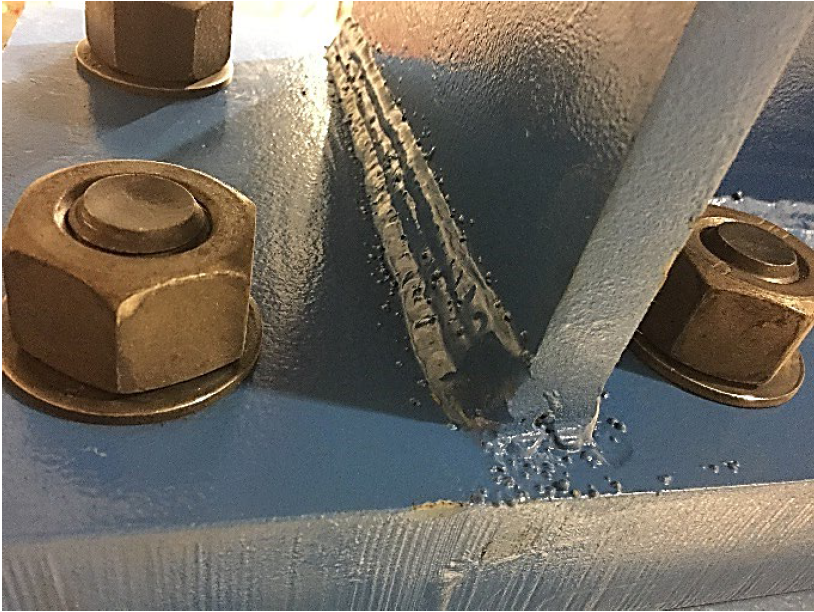 Spatter shown on a weld joint that is painted grey. The spatter appears as little bumps beneath the paint coating.