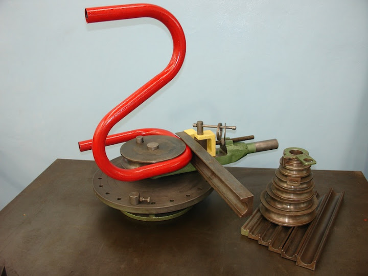 A worker's hand-operated metal bender is used to bend a piece of tubing.