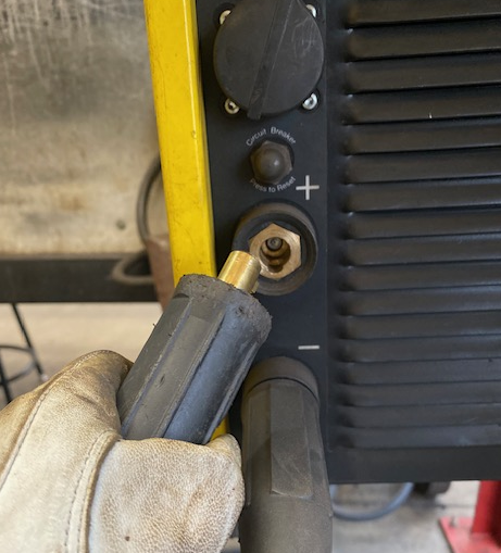 An image showing the end of the electrode holder being connected into the positive terminal of a welding machine.