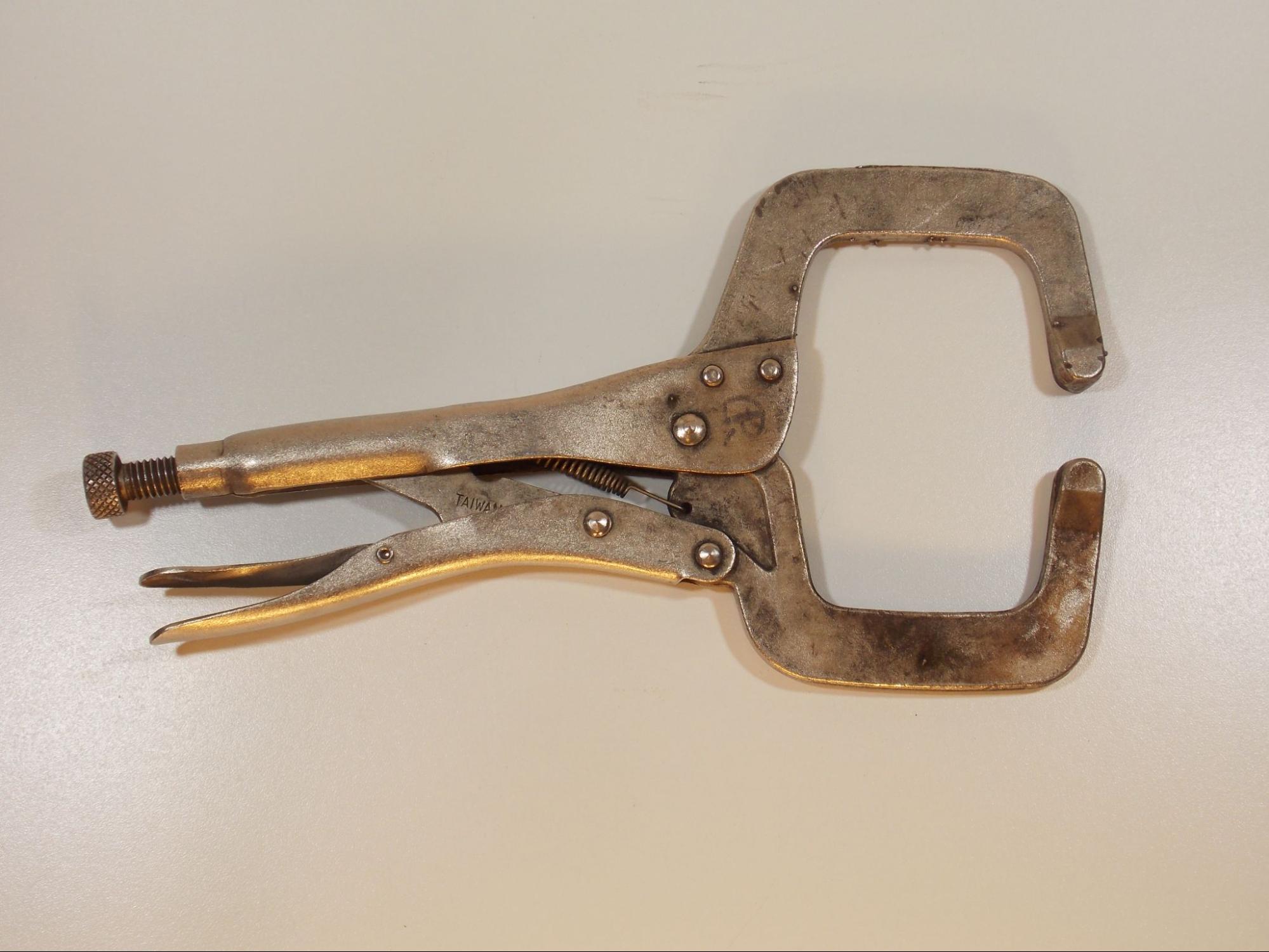 A #11 locking clamp, which looks lik a set of pliers with large metal C-shaped jaws. The plier handles have a built in spring loaded locking mechanism to tighten the clamp and lock it in place.