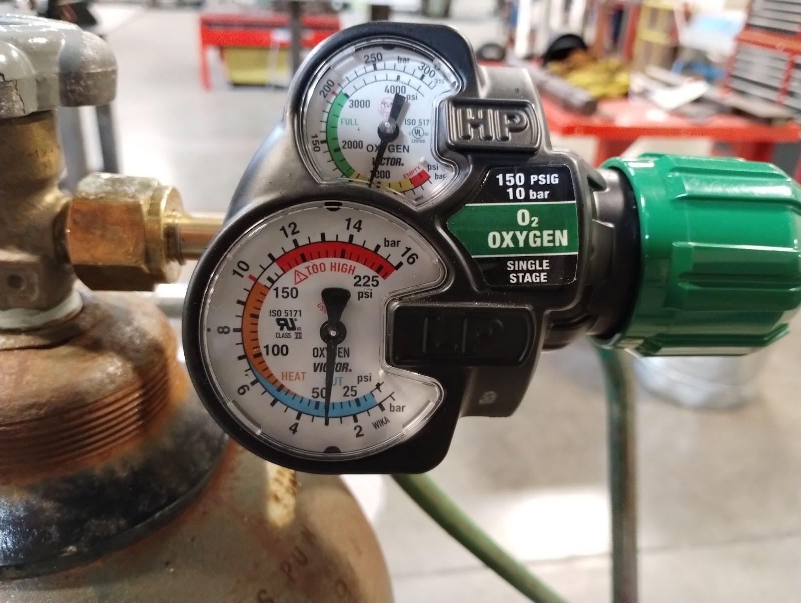 A regulator with two pressure gauges showing the internal pressure of the bottle and the working pressure. The top pressure gauge, which is smaller, shows the internal pressure of the bottle. The bottom gauge is slightly bigger and shows blue, orange, and red levels along the dial. It is safe to continue cutting as long as the indicator needle on the larger gauge stays out of the red.