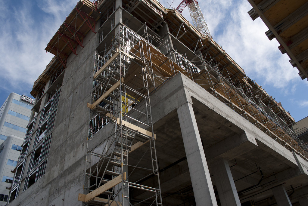 Stairs mounted inside scaffolding are installed next to a building under construction.