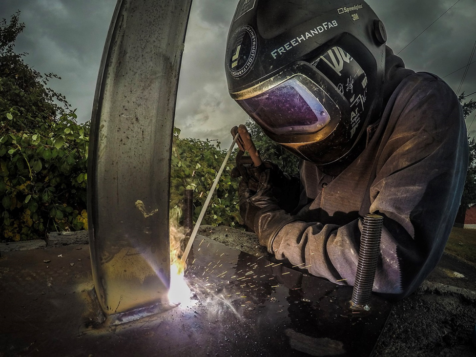 A welder uses SMAW to make a weld on a metal post.