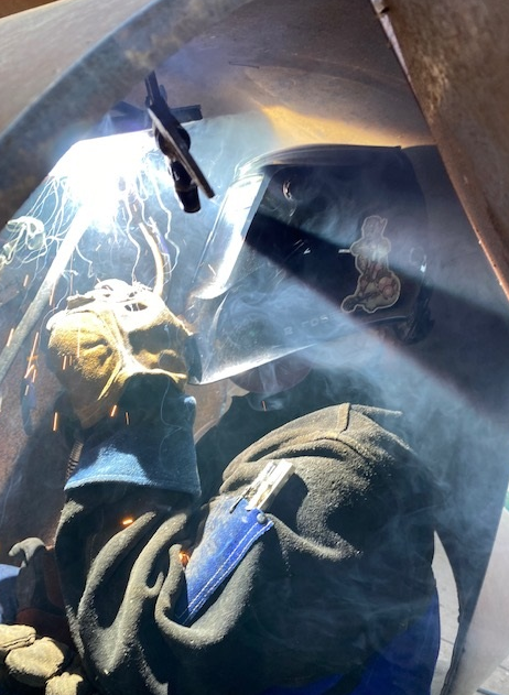 A welder in a confined space uses GMAW in the vertical 45-degree position.