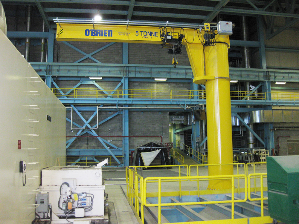 A yellow jib crane with 5 tonne capacity written on it is in a building.