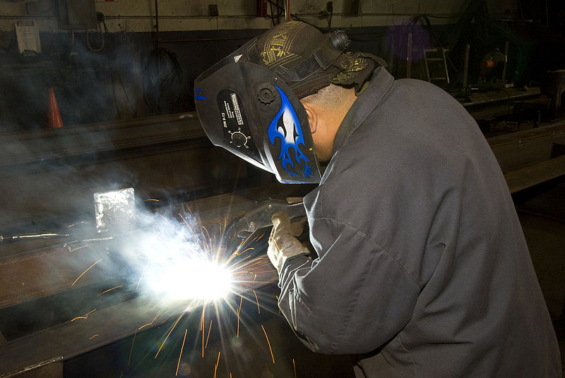 A welder uses FCAW to make a weld on a steel frame.