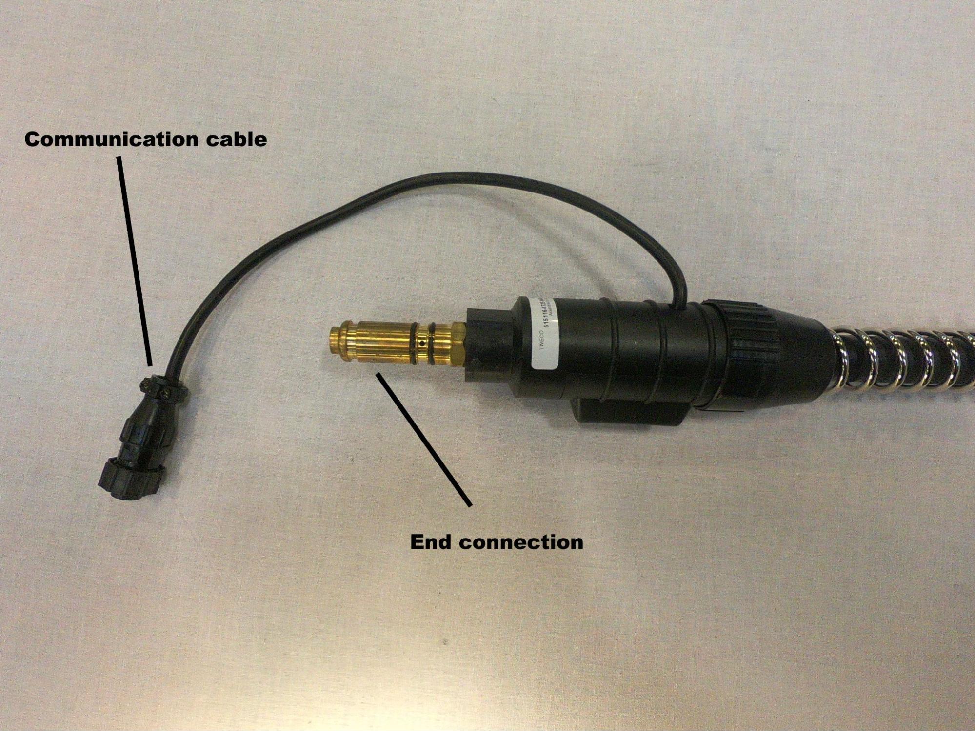 Gun cable end connection with the communication cable attached. The communication cable is a small side cable that branches off of the end connection housing.