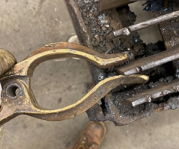 A brass clamp being clapped set on a metal grated table which will serve as the welding table.