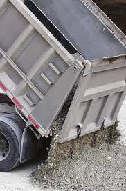 The back of a dump truck, which is made of aluminum, tips a load of gravel onto the ground.