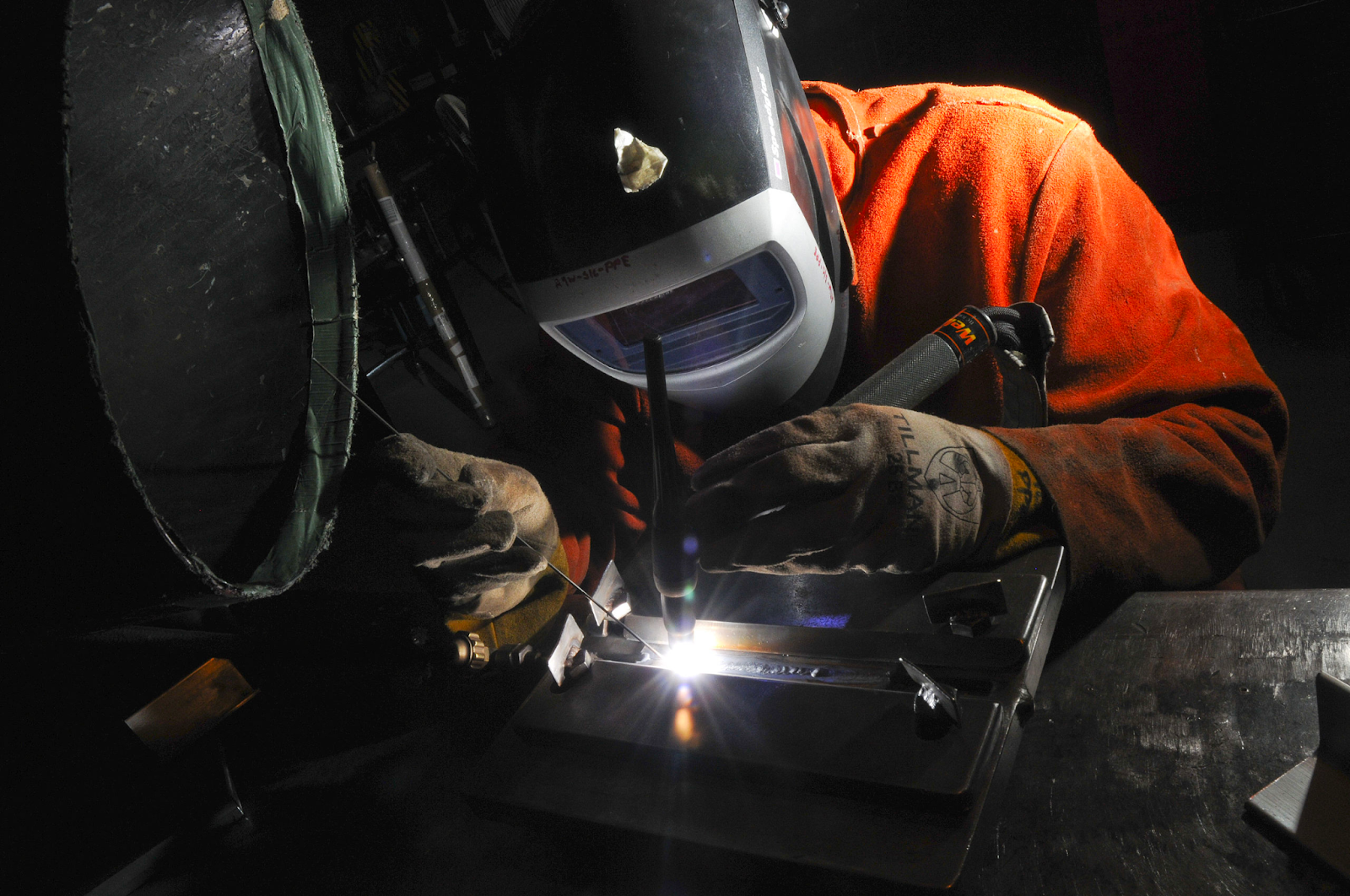 A welder in a leather welding jacket GTA Welding a butt joint using a fixture..