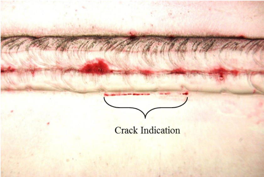 Crack shown on a weld sample that has been tested using liquid penetrant testing. The crack is labeled and is indicated by a thin line about two inches long at the base of the weld bead.