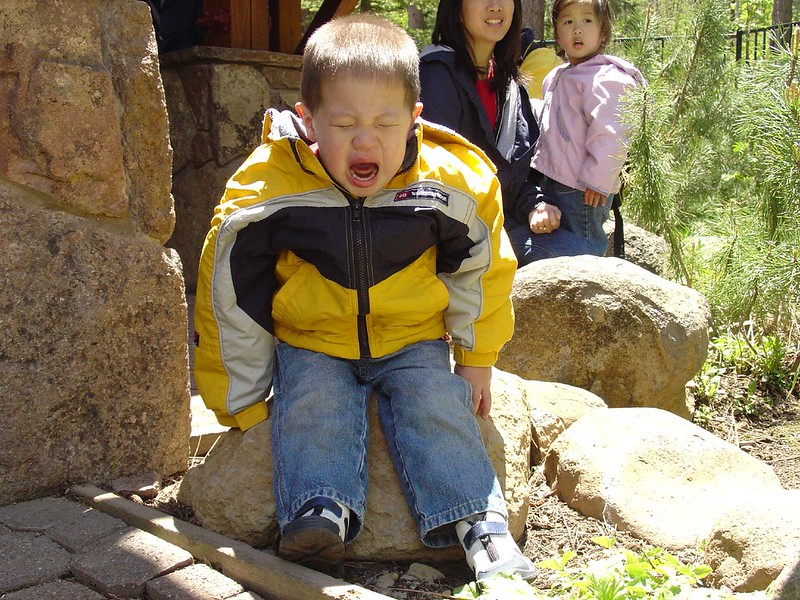 Child crying while sitting on large rock