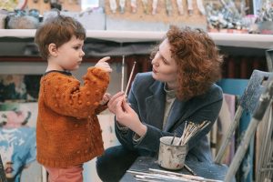 Teacher helping boy choose paintbrush