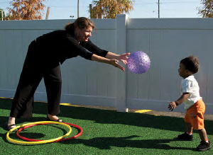 Toddler playing with a ball and teacher