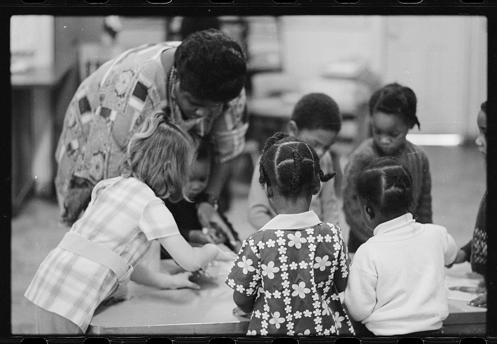 A Teacher at a table with children.