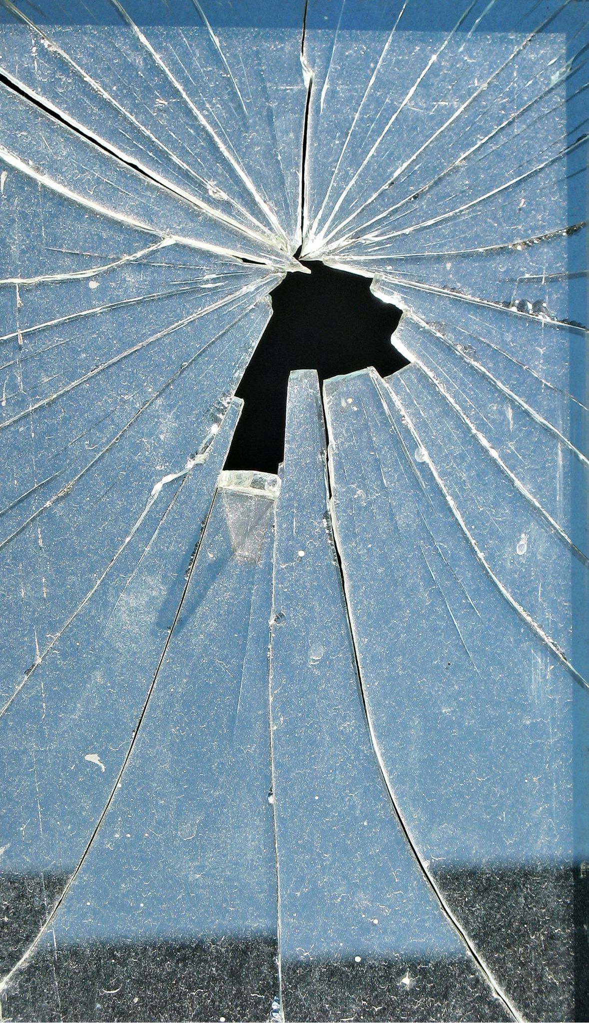 Close-up photograph revealing a shattered window, displaying dirt accumulated from long-term neglect.