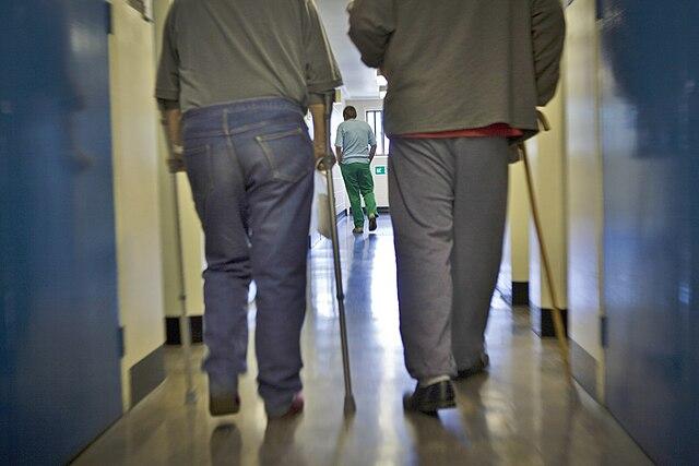 Image of two elderly and disabled prisoners walking down 'A' wing of HM Prison Littlehey in Cambridgeshire, England.