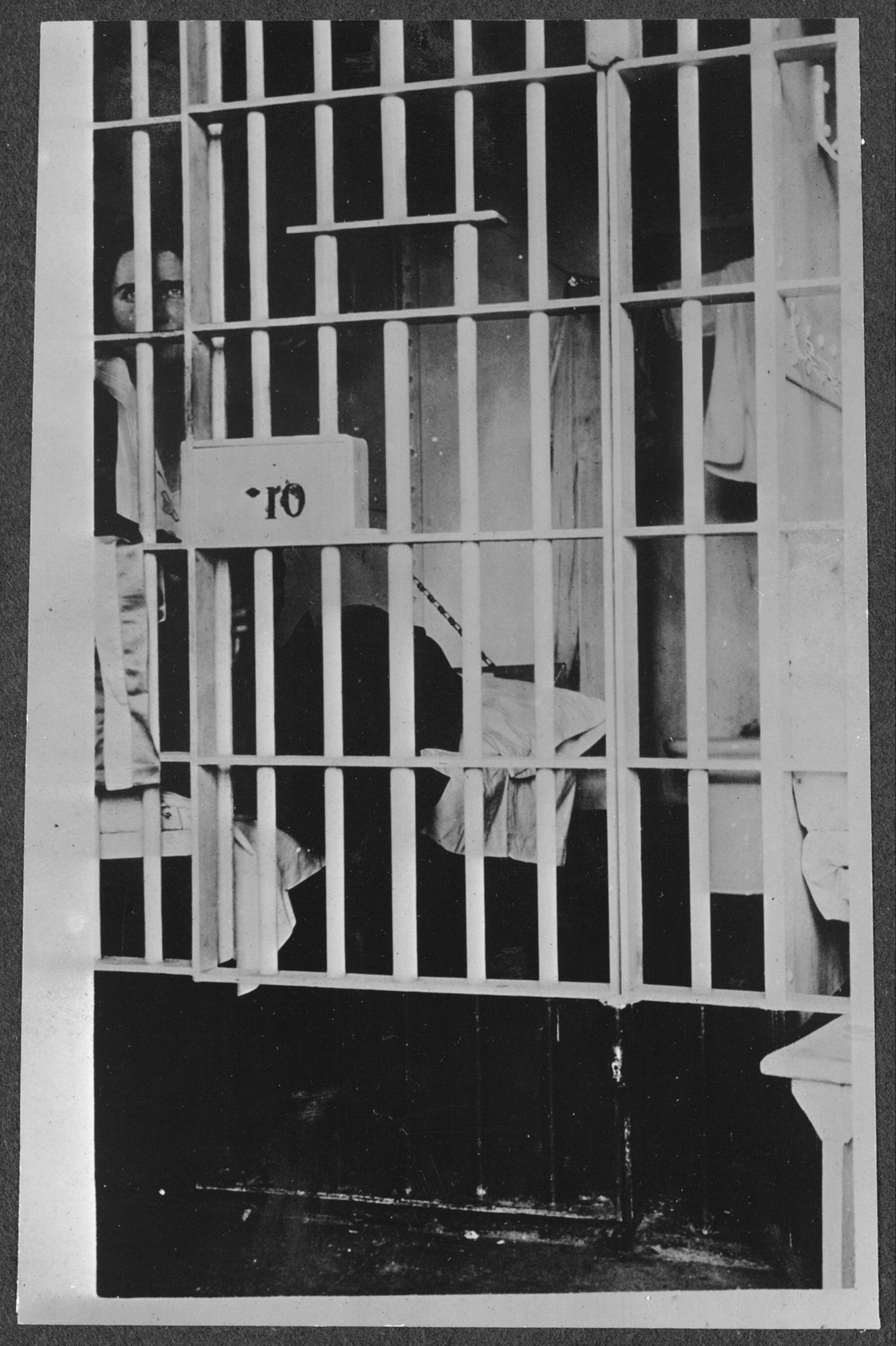 Photograph of Vida Milholland, an avid women’s rights activist, peering through the bars of her jail cell at the Washington D.C. District Jail.