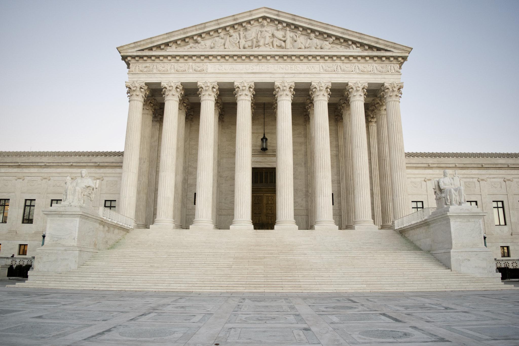 Photograph capturing the stately facade of the interior of the U.S. Supreme Court Building, featuring a grand neoclassical design adorned with majestic ivory-colored marble columns and intricate architectural details.