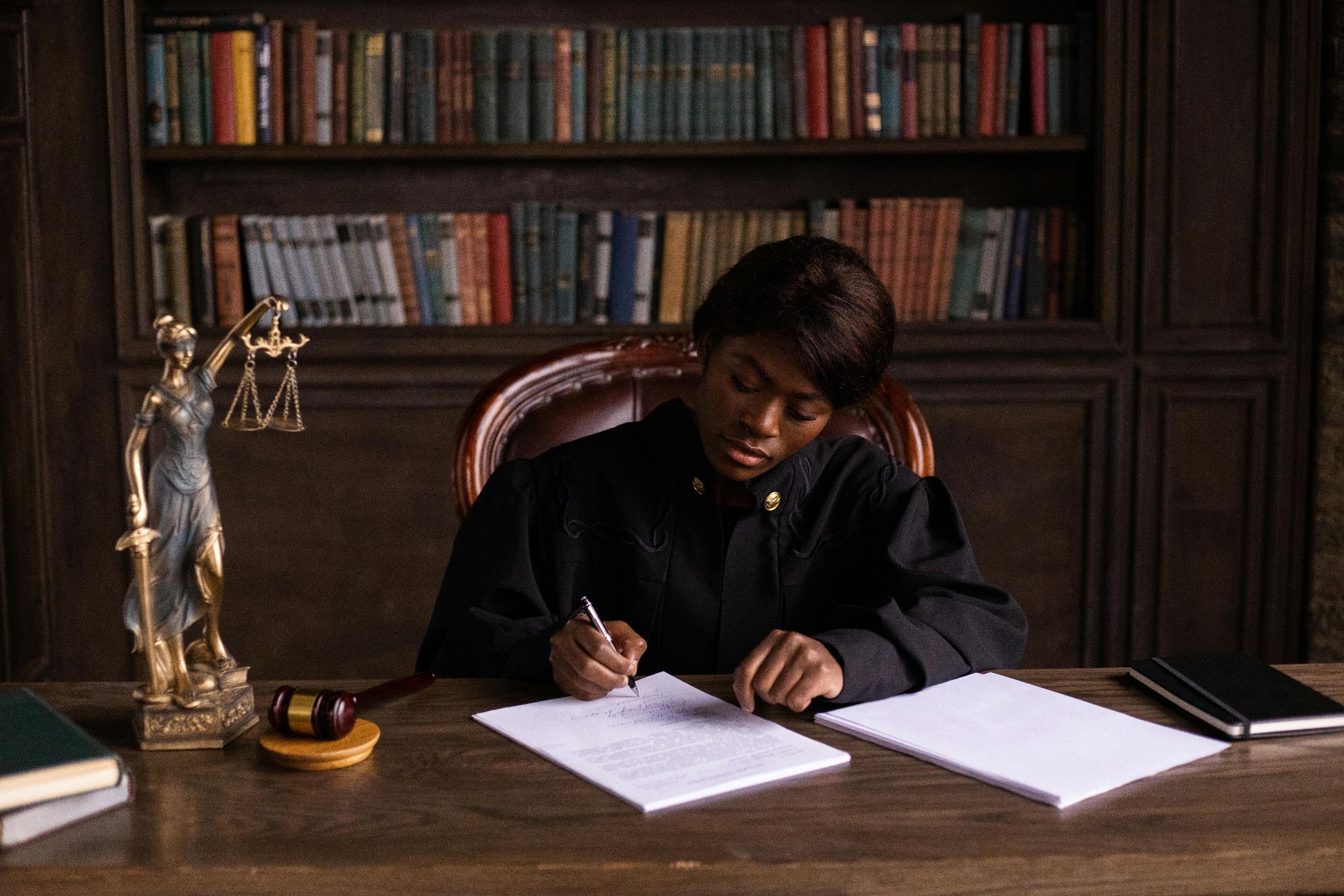 Photograph of a judge at a desk, signing paperwork to finalize a sentencing decision.