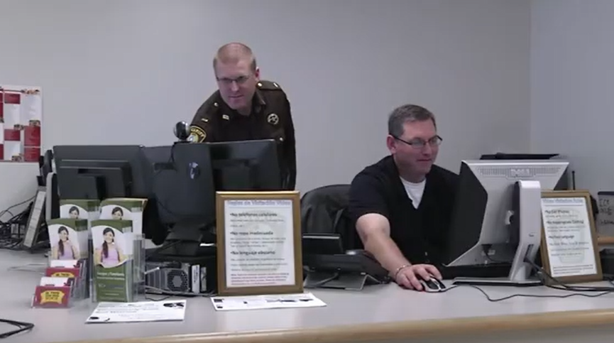 Two community corrections officers working behind the front desk at a correctional treatment facility.