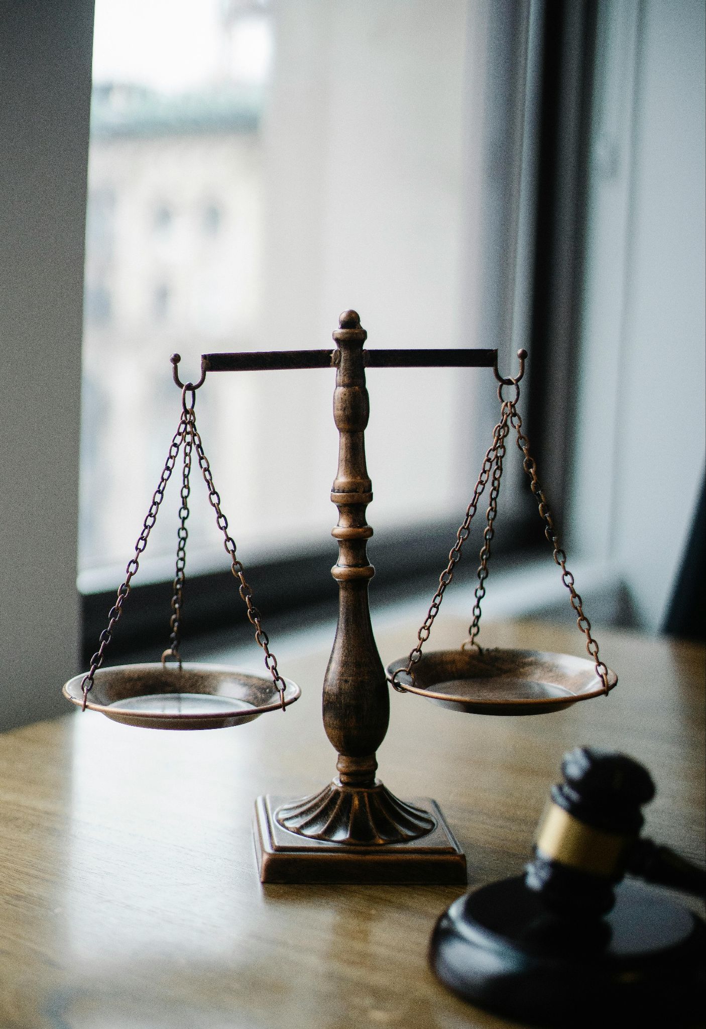 Photograph showing the scales of justice and a gavel resting on a wooden desk.