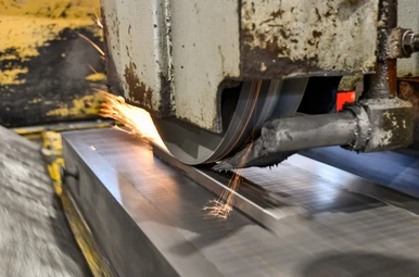 Close up picture of surface grinder moving, sparks shooting off the back of the part.