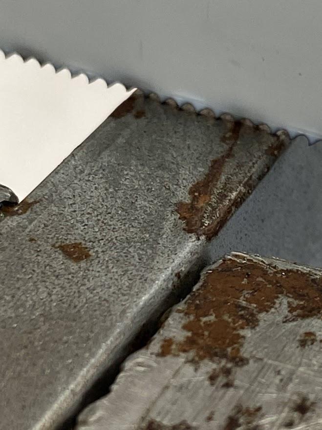 An enlarged photo of several teeth in contact with metal to be cut.