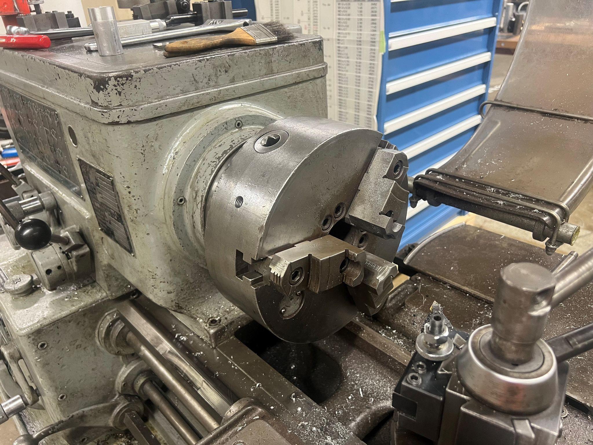 Three jaw chuck on a manual lathe. Tool post in foreground.