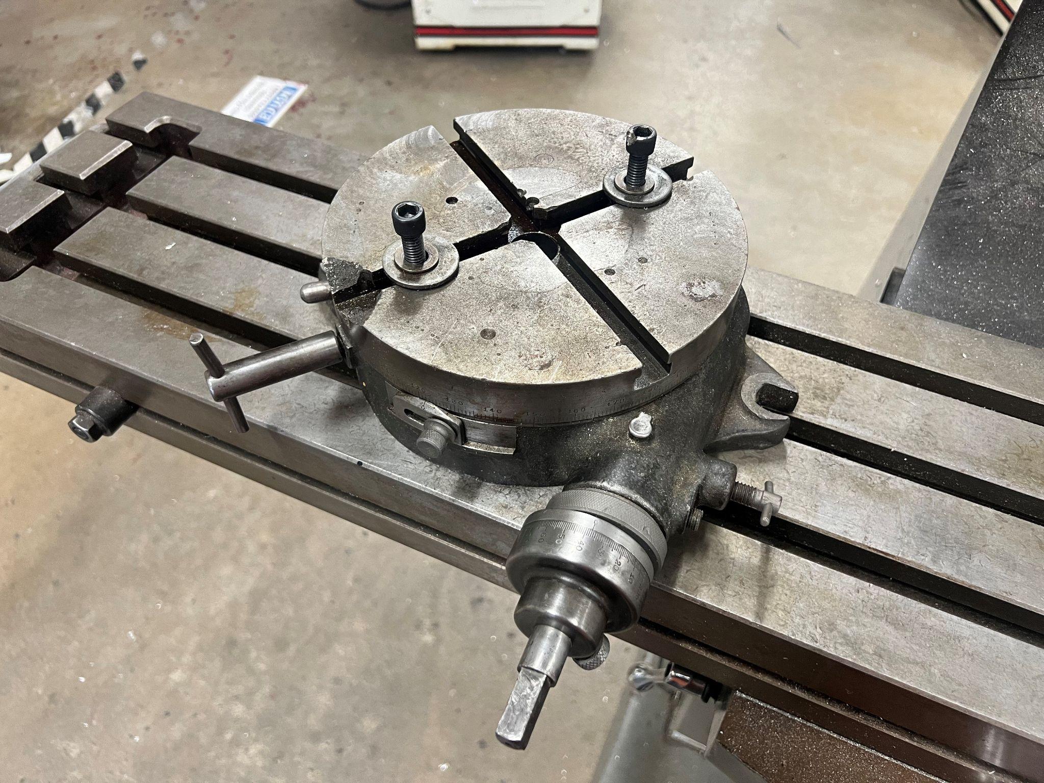 Picture of a rotary table sitting on a vertical milling table.