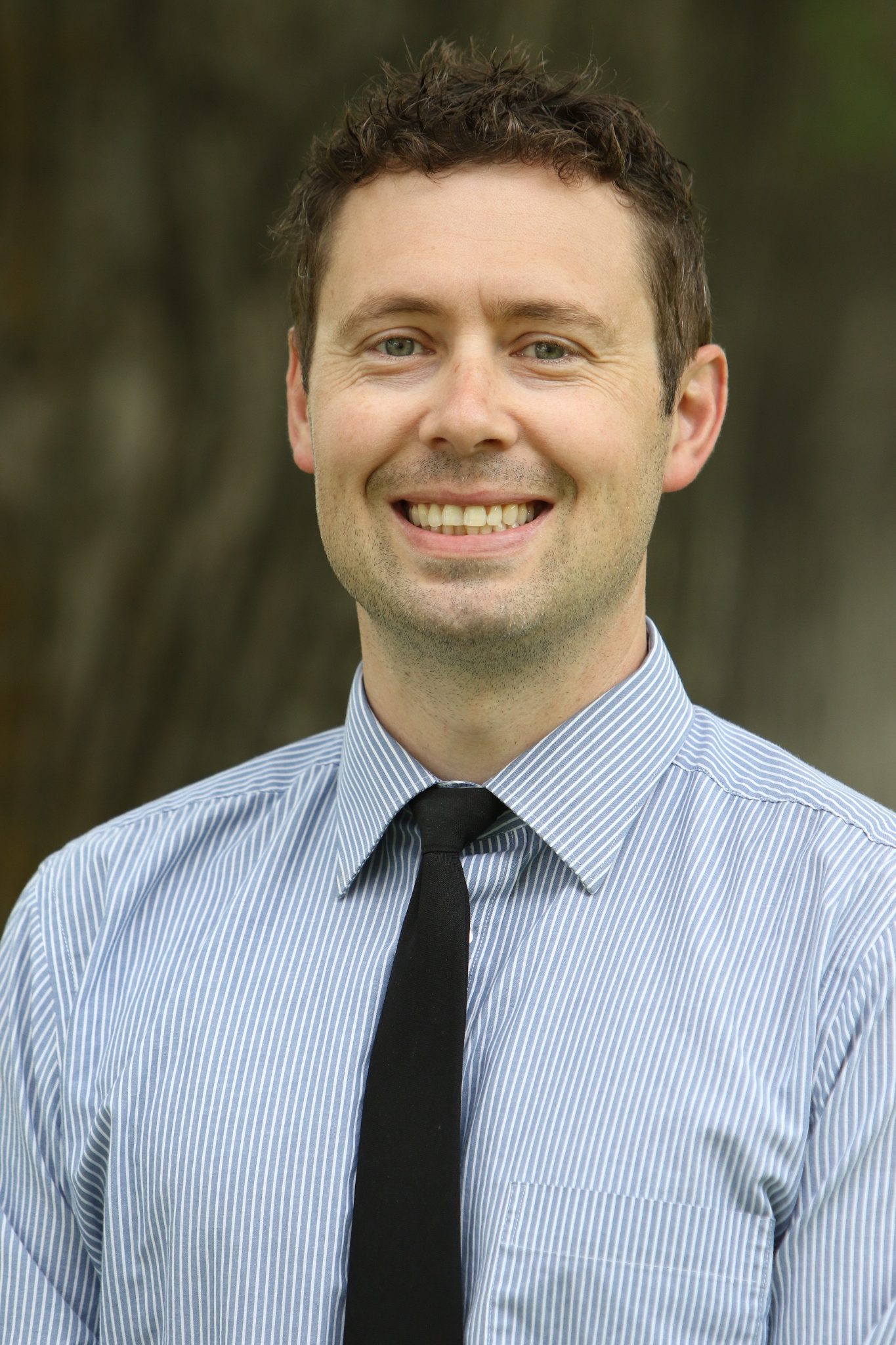 Picture of a man wearing a blue shirt and black tie