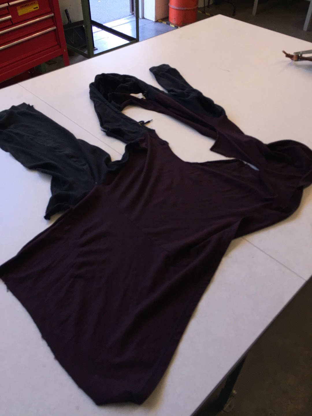 A torn shirt is laid out on a table with a sleeve torn from the rest of the garment.