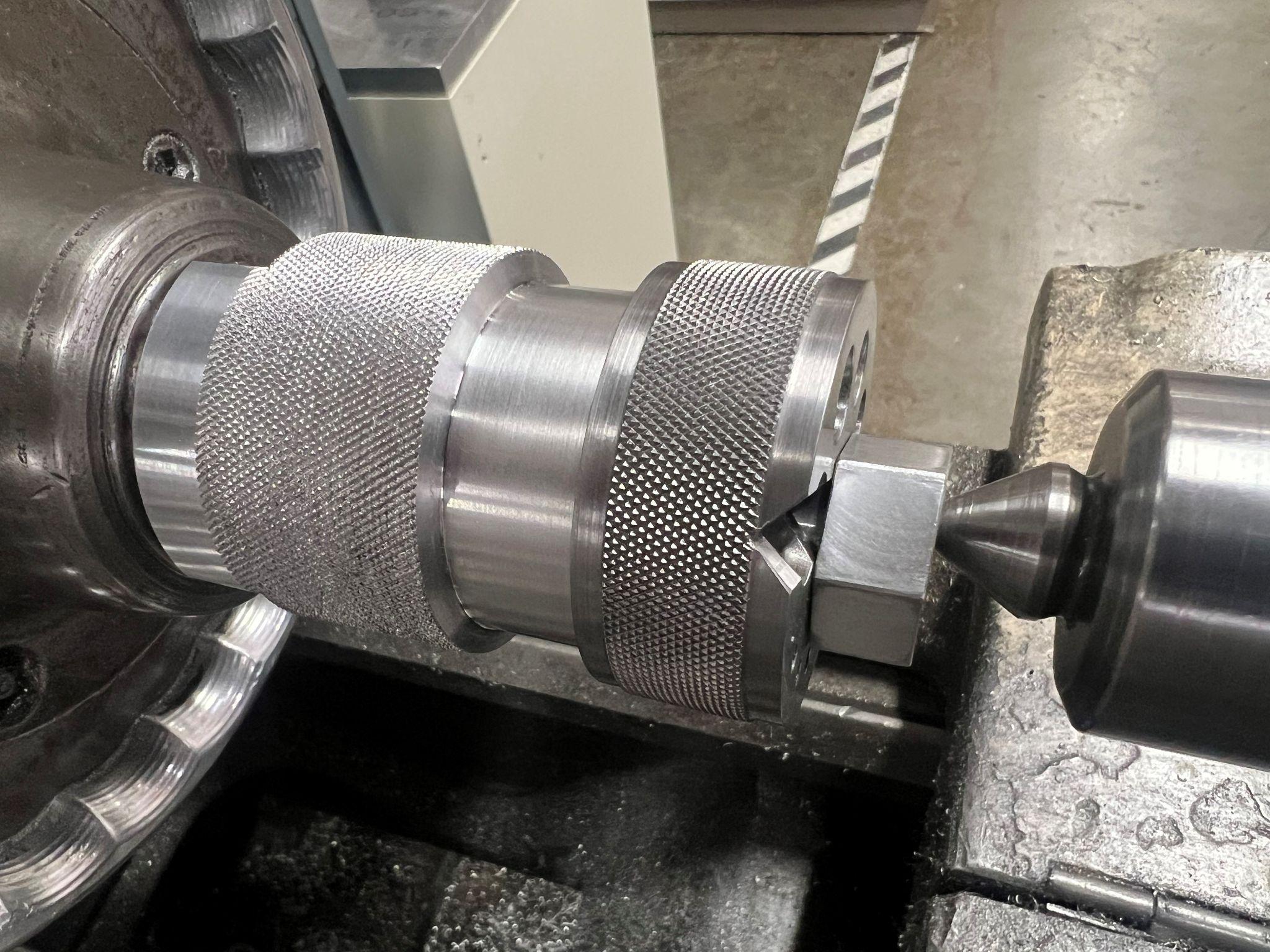 The finished part is shown on the fixture with tailstock support. Turning, knurling, and cutting the relief were done on this set up.