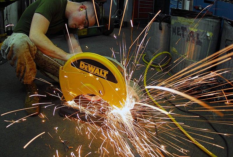 Worker using an abrasive saw to cut material. Sparks are flying everywhere.