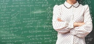 Image of a professional analyst standing with arms crossed in front of a chalkboard filled with complex mathematical equations.