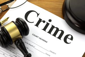 A picture of a court hearing form with crime written at the top together with a gavel, block, pen and glasses.