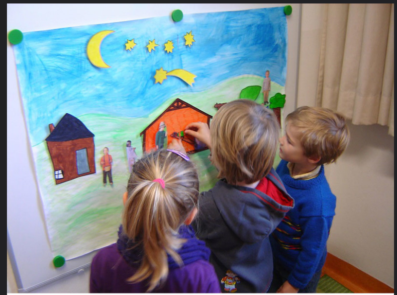 Three children working cooperatively on a story. The children are demonstrating age-appropriate social skills.