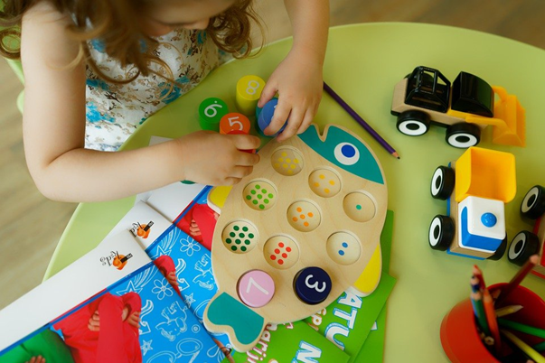 A child plays a math game in which a number of dots are matched with a numeral.