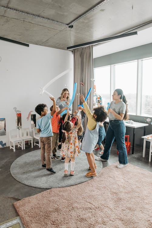 Preschool classroom with children doing movement activity as a mom engages with the activity.