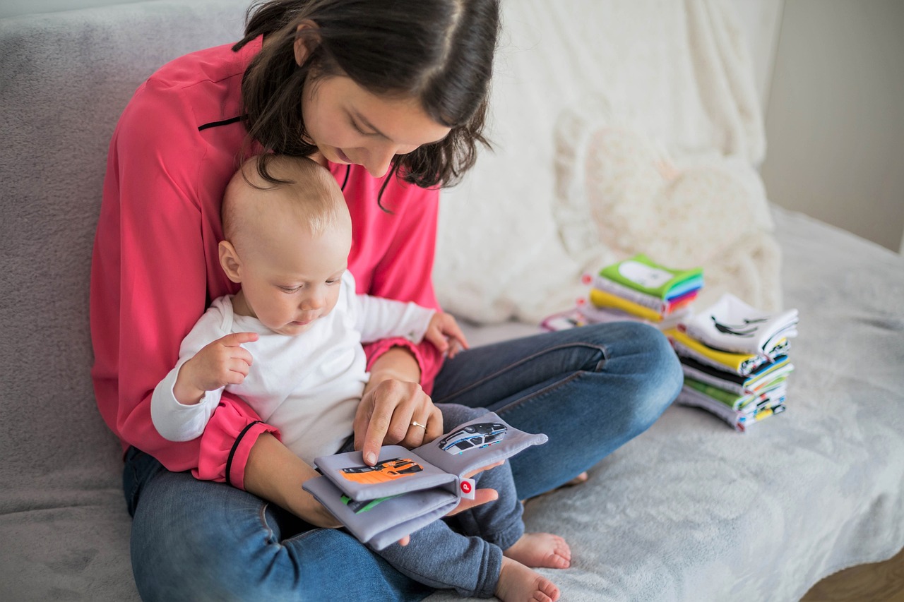 Family Friend and Neighbor provider and child sit on a couch and read a picture book.