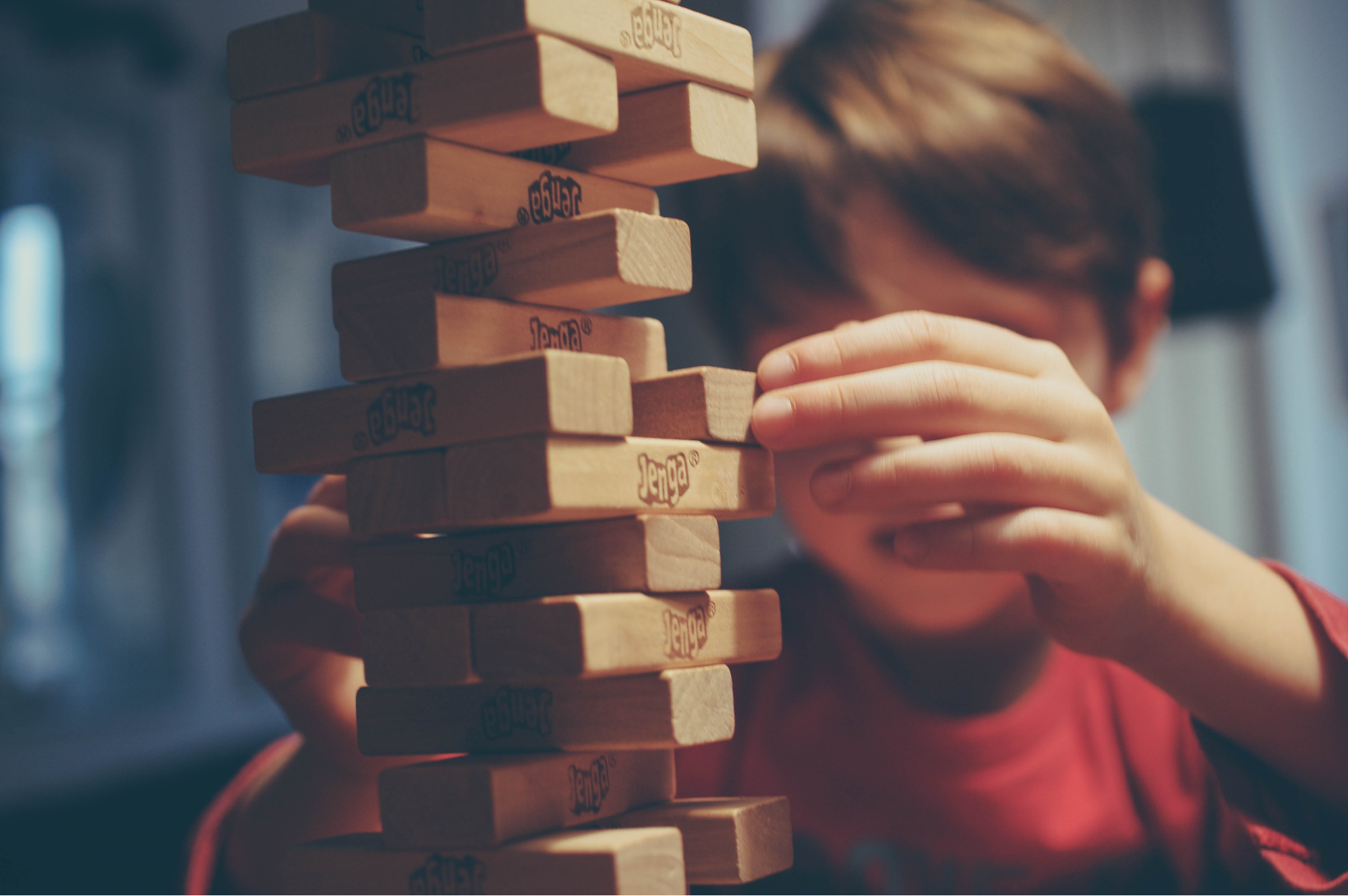 Young boy building a tower with Jenga blocks. Jenga blocks balance on connection, as do behaviors.