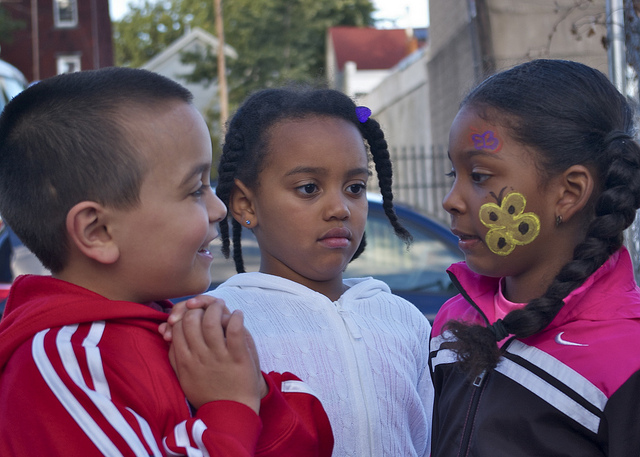 Three kids talking on the street and smiling