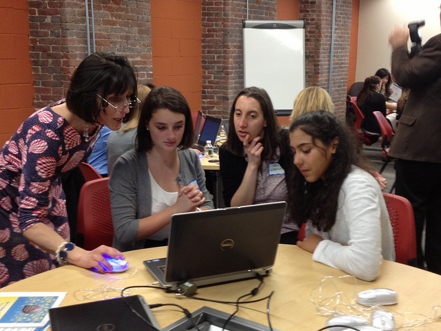 A teacher helping a group of students on a laptop