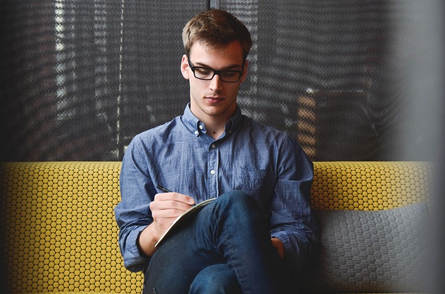 A very professional looking man, sitting with his legs crossed, writing in a journal