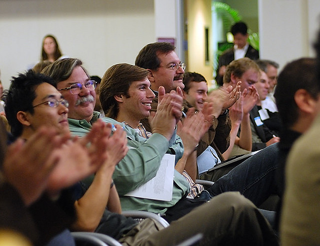 An audience smiling and clapping