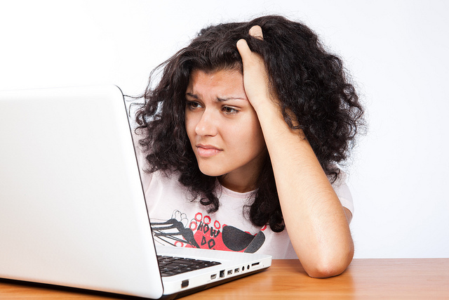 A college student looking stressed out on the computer