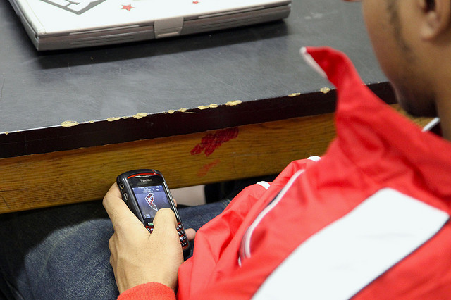 A student sneakily using his cell phone while in class