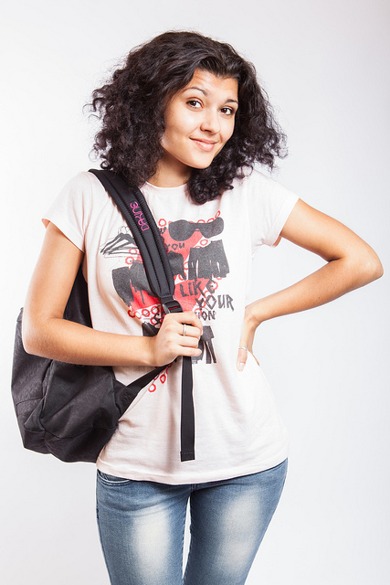 A college student standing unsure with her backpack