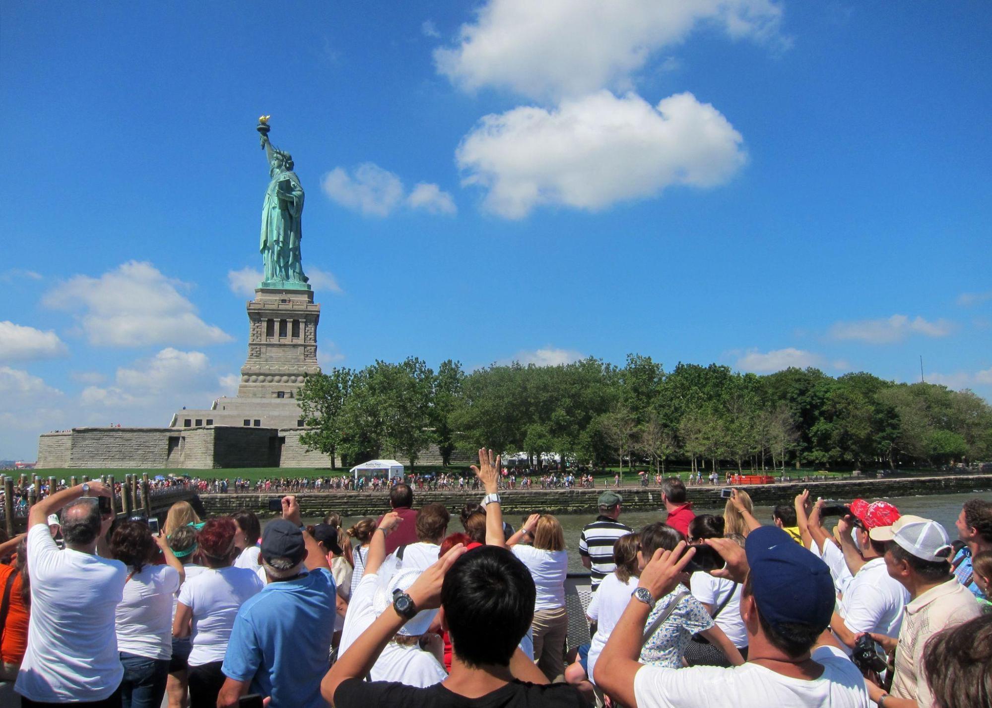 Dozens of people view the Statue of Liberty from a boat.